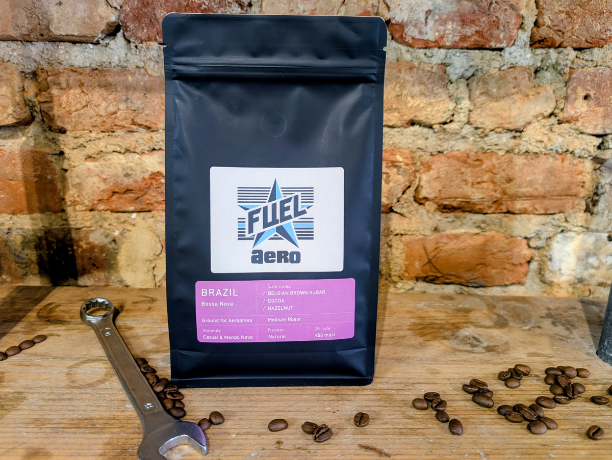 Bag of Fuel Aero Brazil single origin coffee, ground for AeroPress, on a shelf in front of a brick wall with a retro spanner