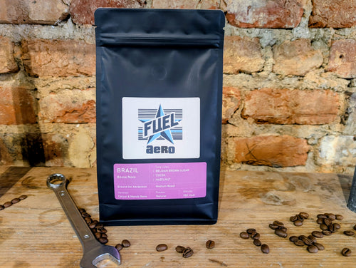 Bag of Fuel Aero Brazil single origin coffee, ground for AeroPress, on a shelf in front of a brick wall with a retro spanner