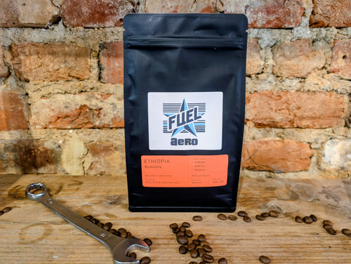 Bag of Fuel Aero Ethiopia single origin coffee, ground for AeroPress, on a shelf in front of a brick wall with a retro spanner